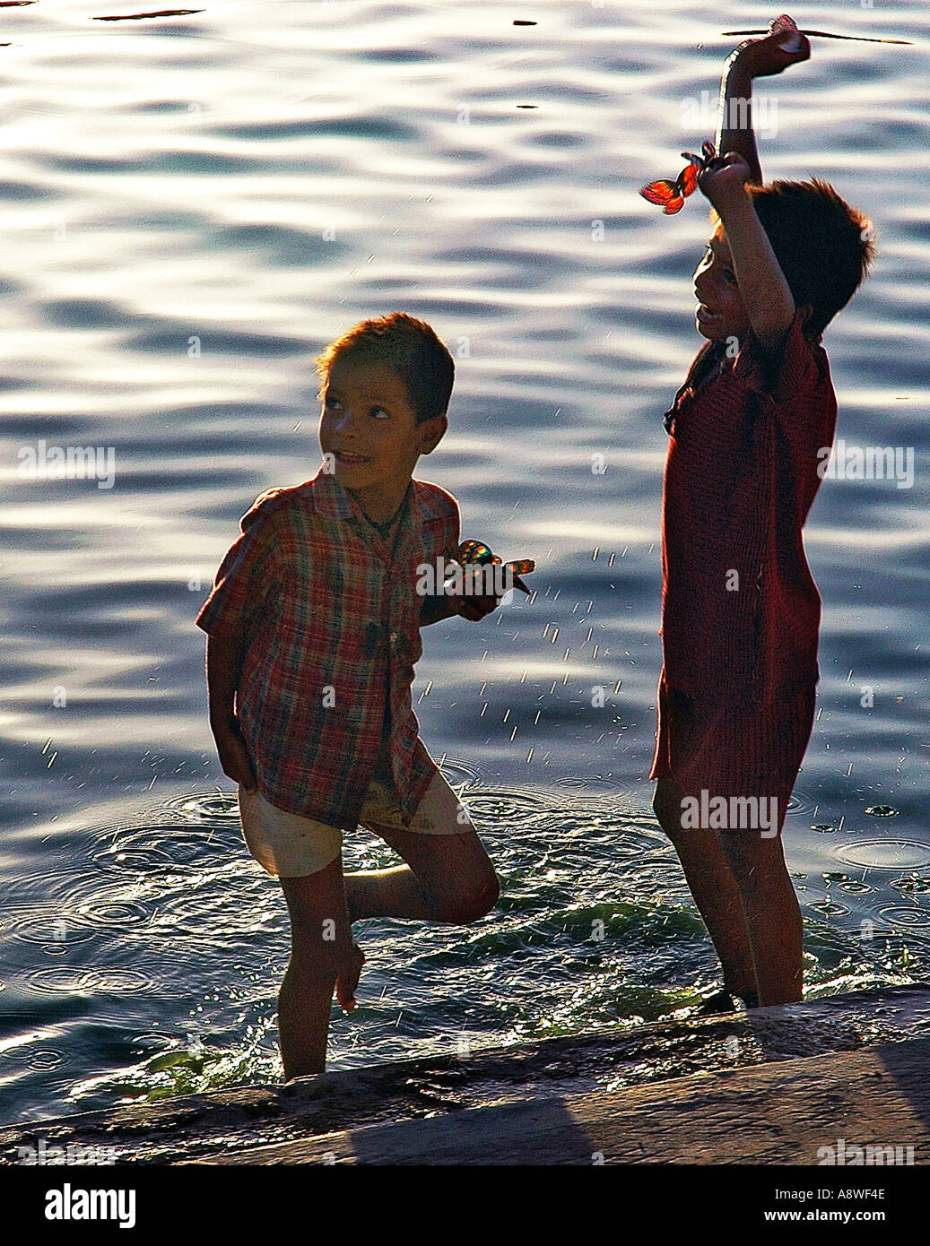 SUB90542 Two Indian children playing with toy butterflies in river Shipra Ujjain Stock Photo