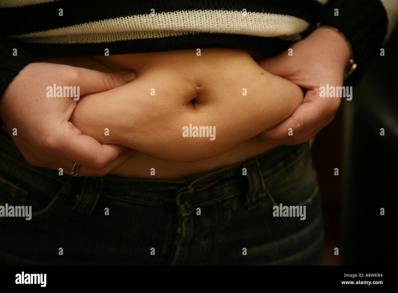 fat woman feeling rolls of fat round waist Stock Photo