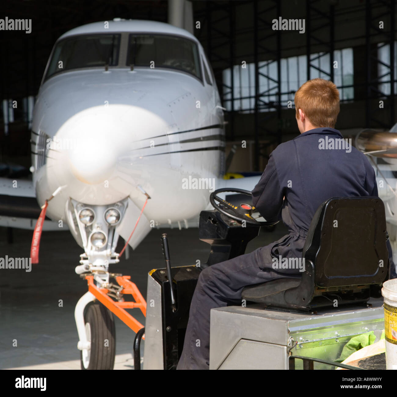 Young man towing a King Air aircraft from the hangar. UK. Stock Photo