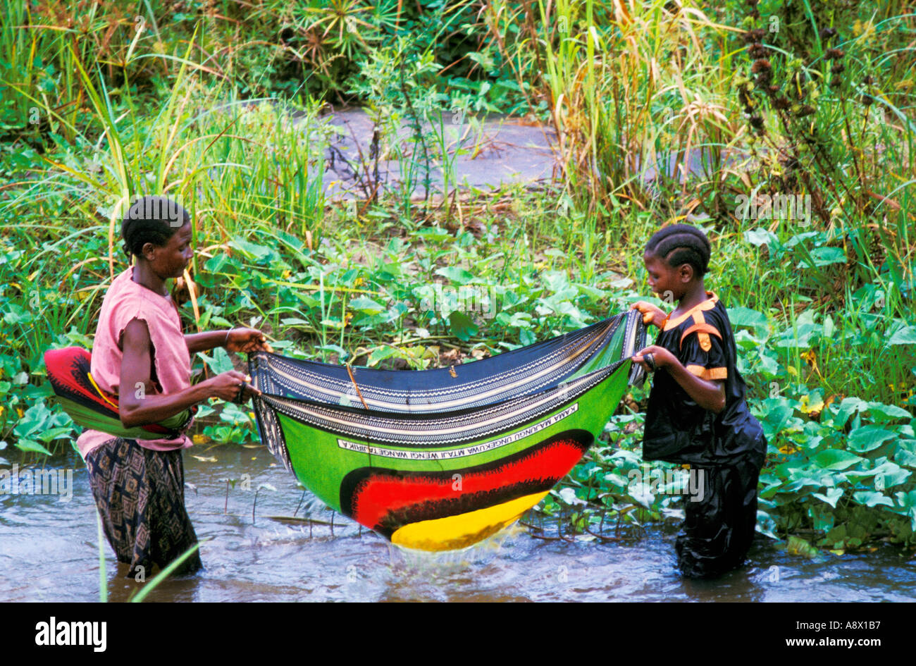 Africa KENYA Malindi Kenyan mother and daughter use a traditional kanga cloth as a net to capture fish in the river Stock Photo