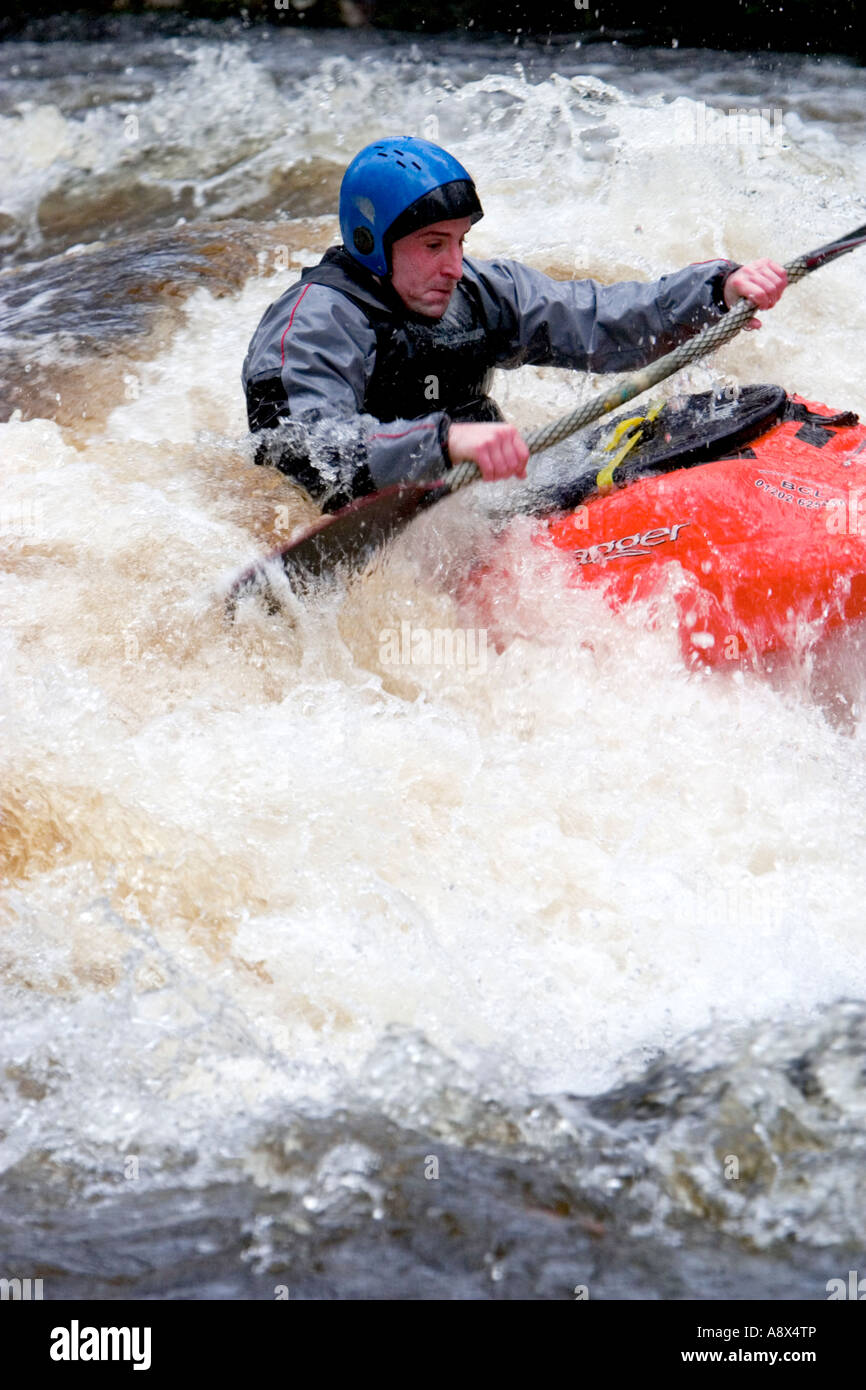 A canoeist battles the torrent waters of the River Dart in Devon England Stock Photo