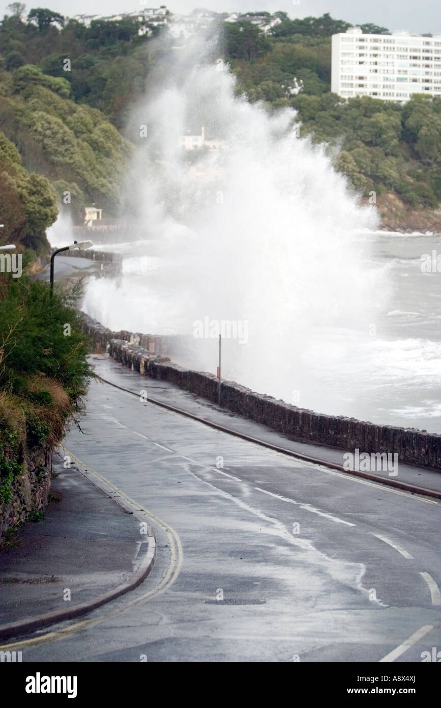 Rough seas hitting the wall defences causing massive explosions of sea water cascading over the roadside as cars run the gauntle Stock Photo