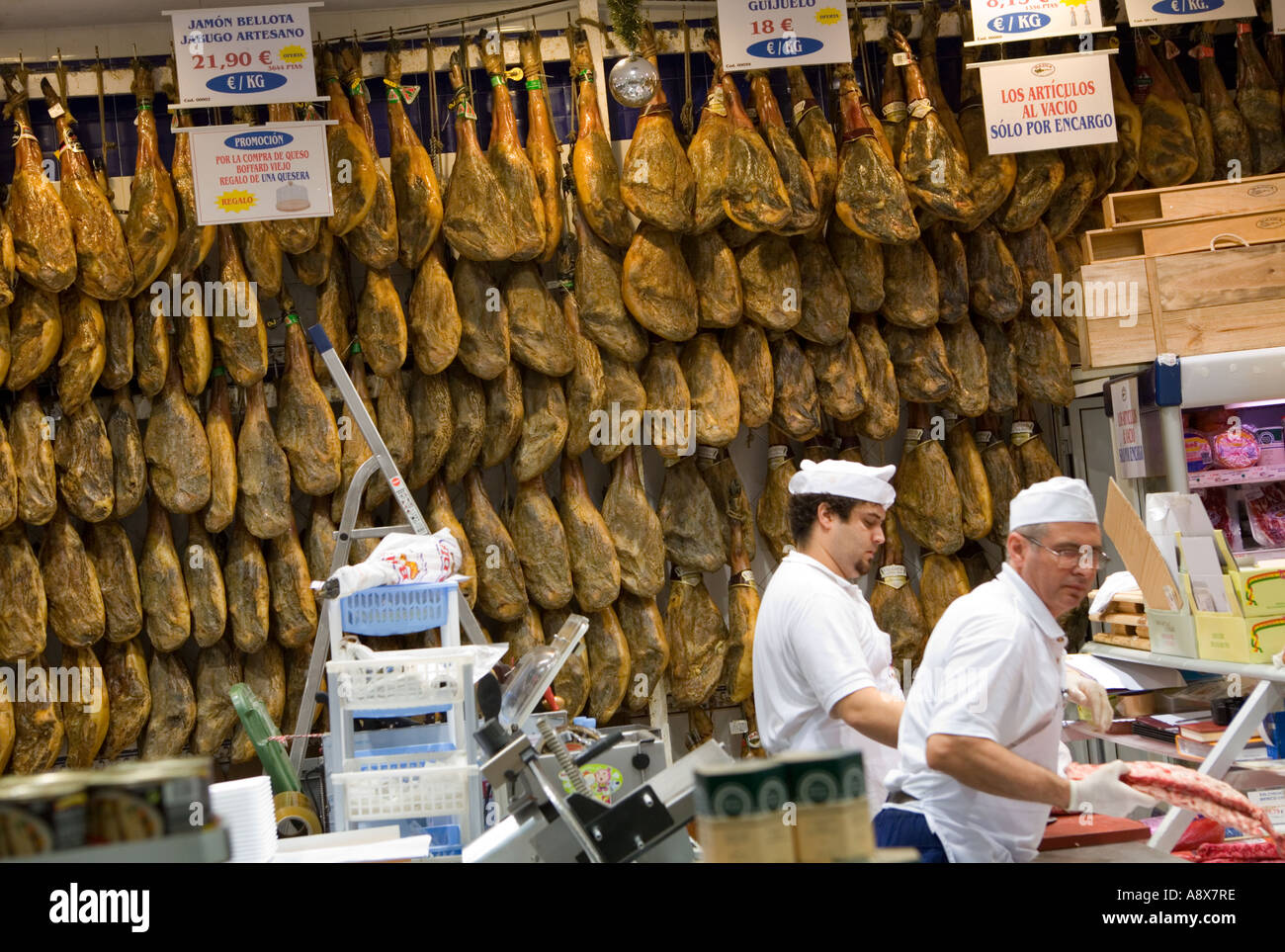 Serrano hams hanging on wall in Spanish delicatessen Stock Photo