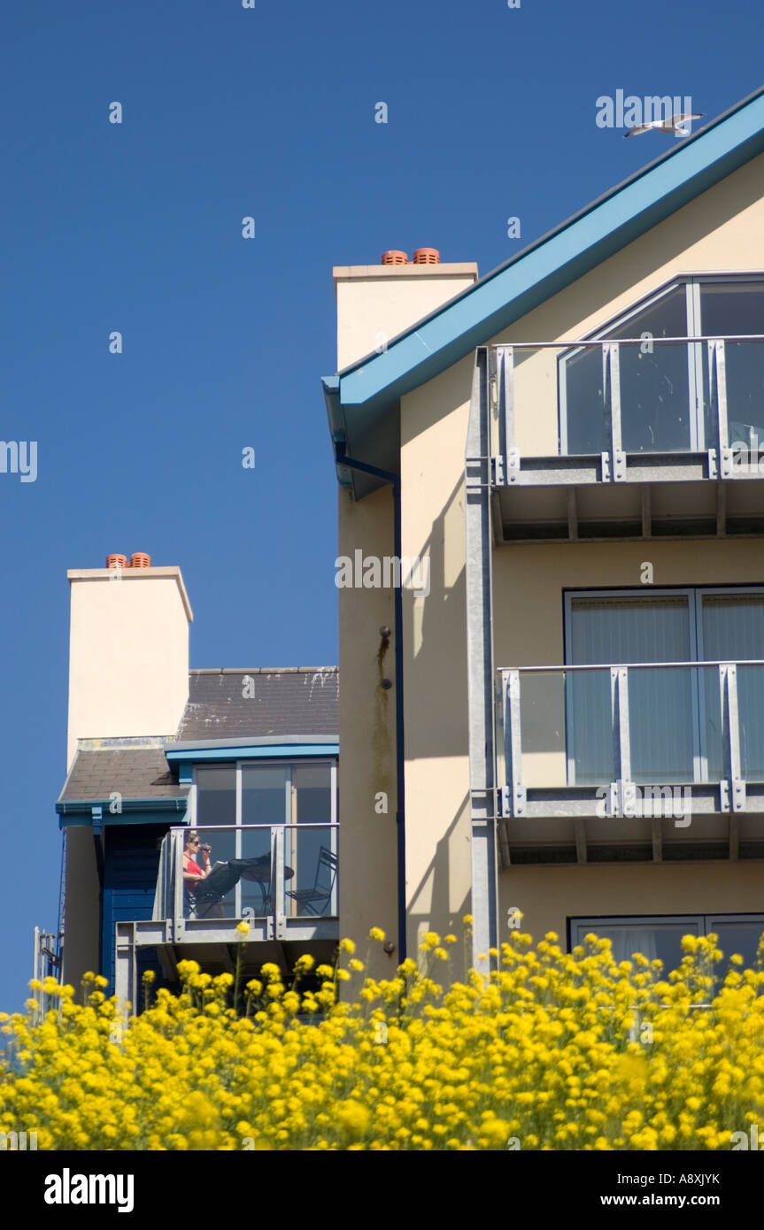 woman sitting on the balcony of her flat in a block of modern flats overlooking Aberystwyth