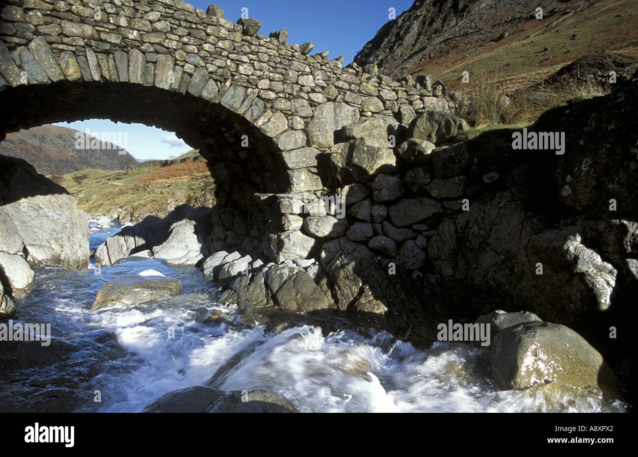 Footbridge over Grains Gill near Seathwaite in Borrowdale Cumbria A naturally running clean mountain stream Stock Photo