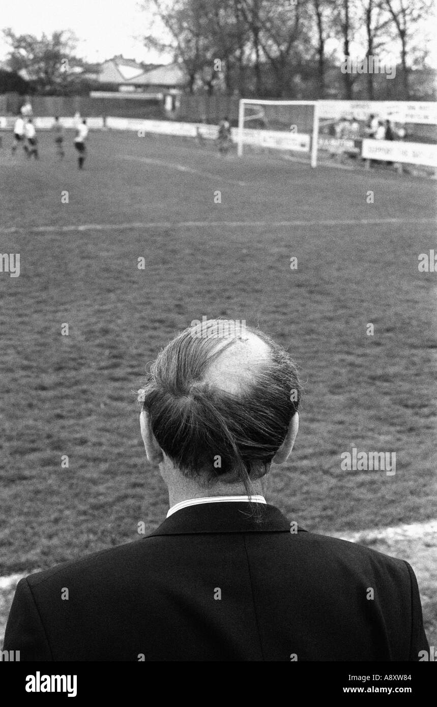 a bald man watches a football match Stock Photo