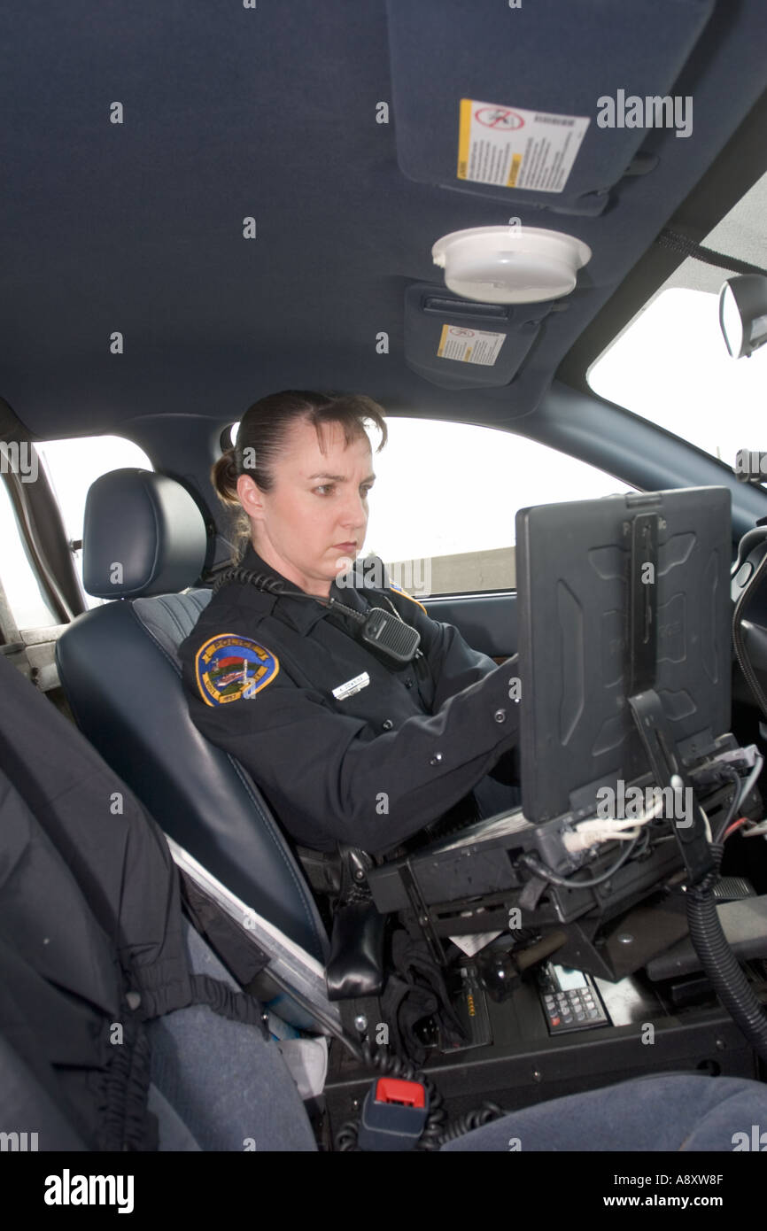 Female police officer using laptop in her police cruiser to check a drivers license. Sioux City, Police Department, Iowa, USA. Stock Photo