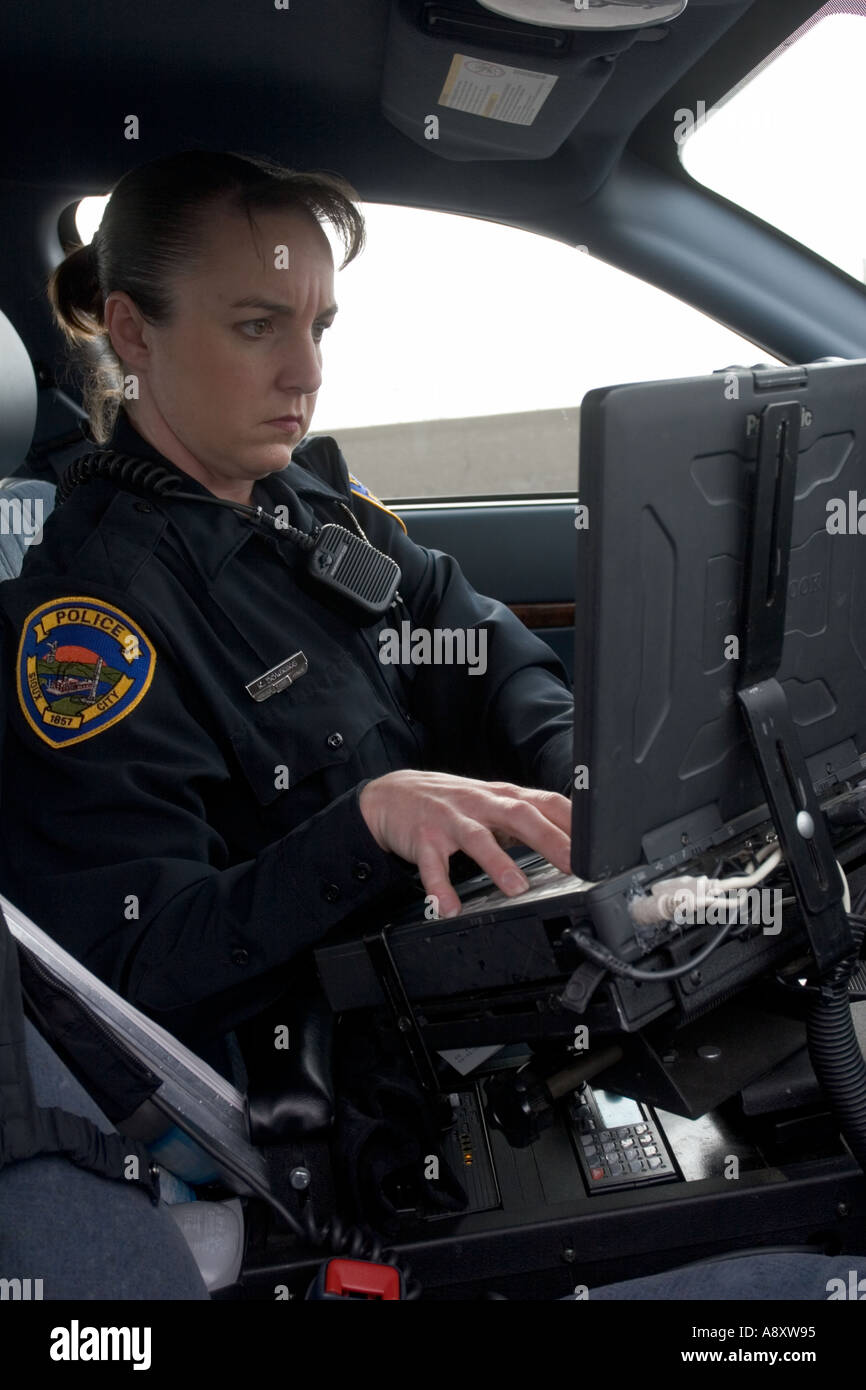 Female police officer using laptop in her police cruiser to check a drivers license. Sioux City, Police Department, Iowa, USA. Stock Photo