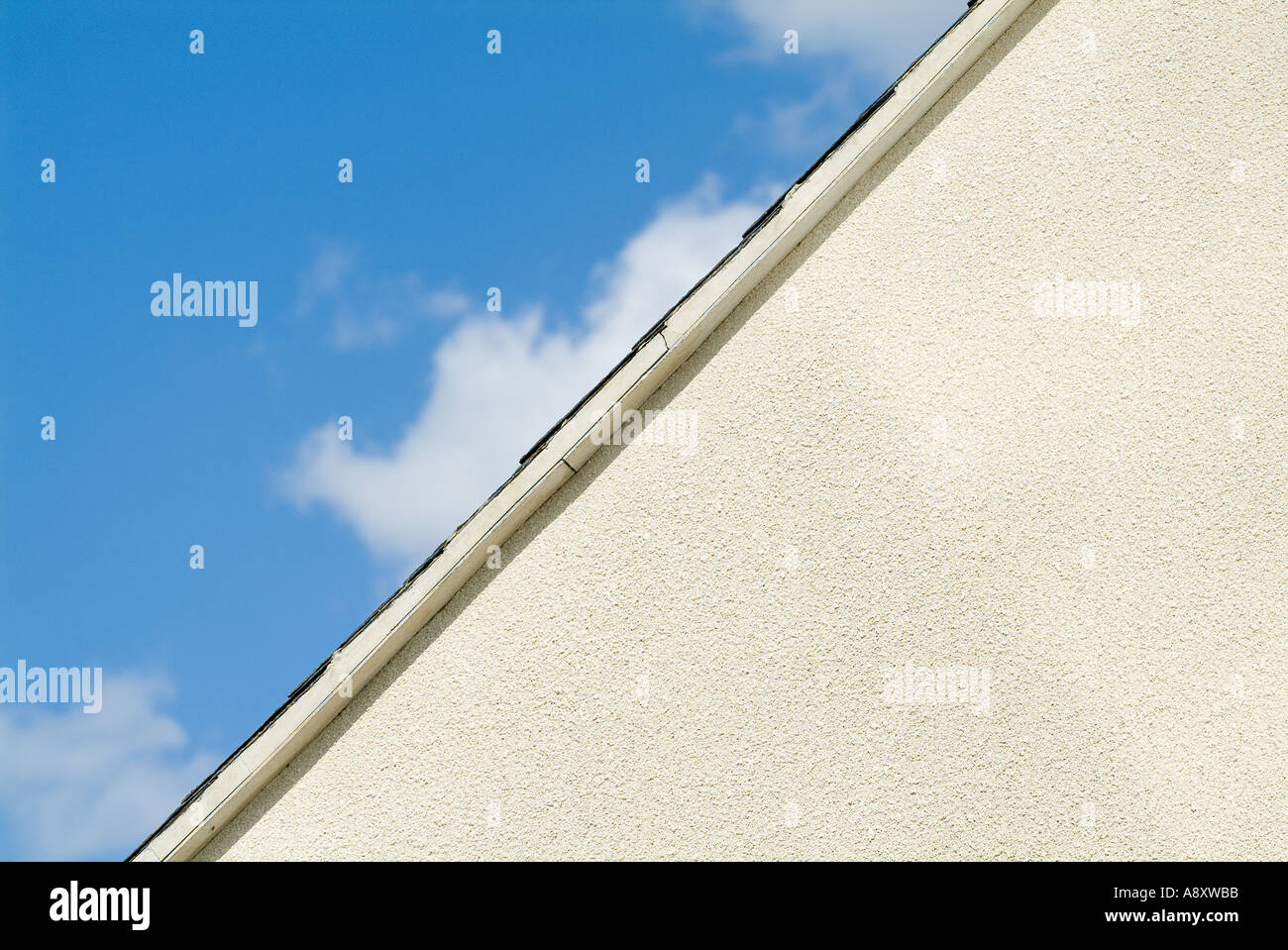 Front apex of building showing white pebble dashing, rendering, and blue sky Stock Photo