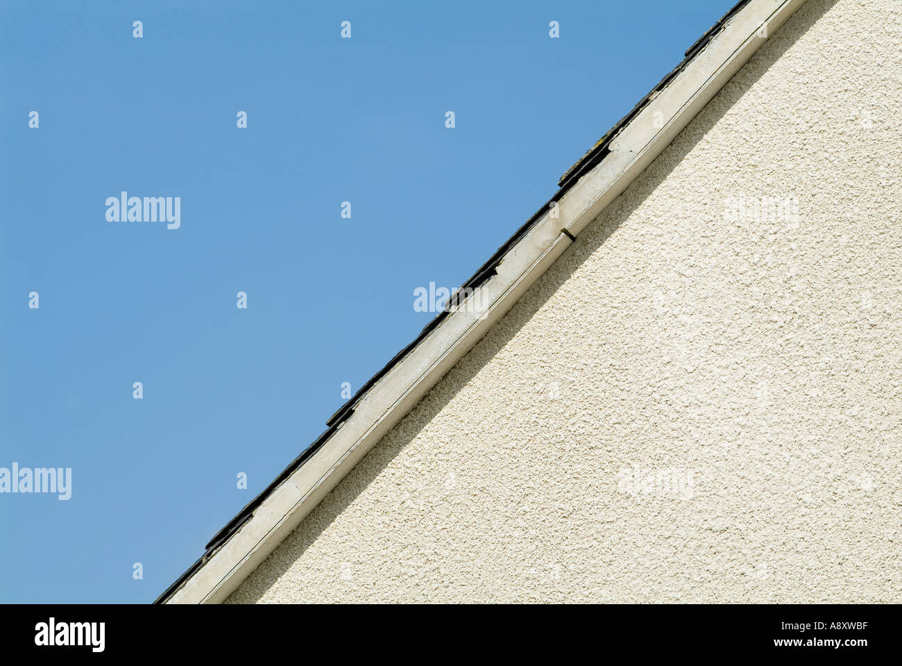 Front apex of building showing white pebble dashing, rendering, and blue sky Stock Photo