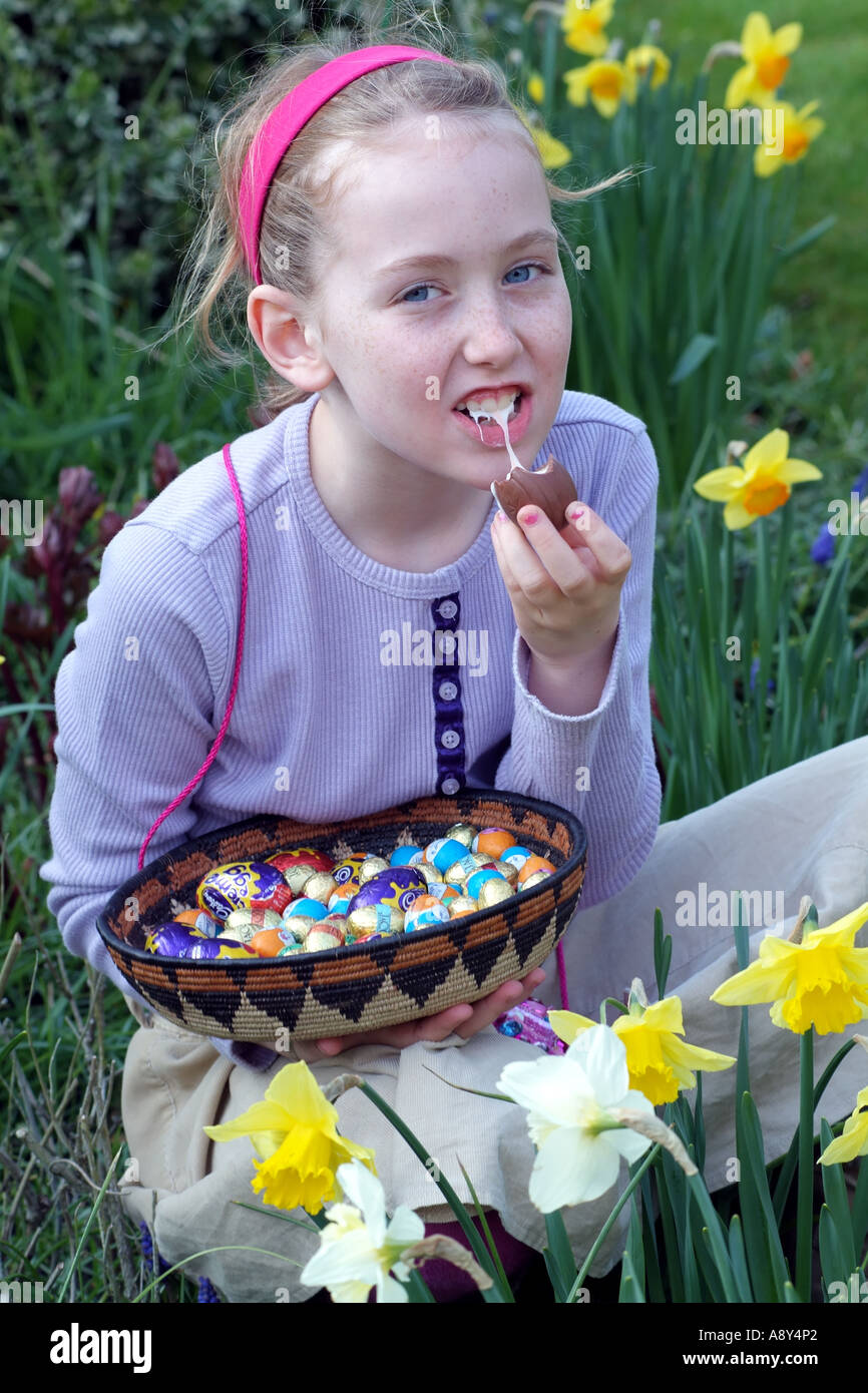 Easter egg hunting. A little girl eating chocolate eggs. English garden