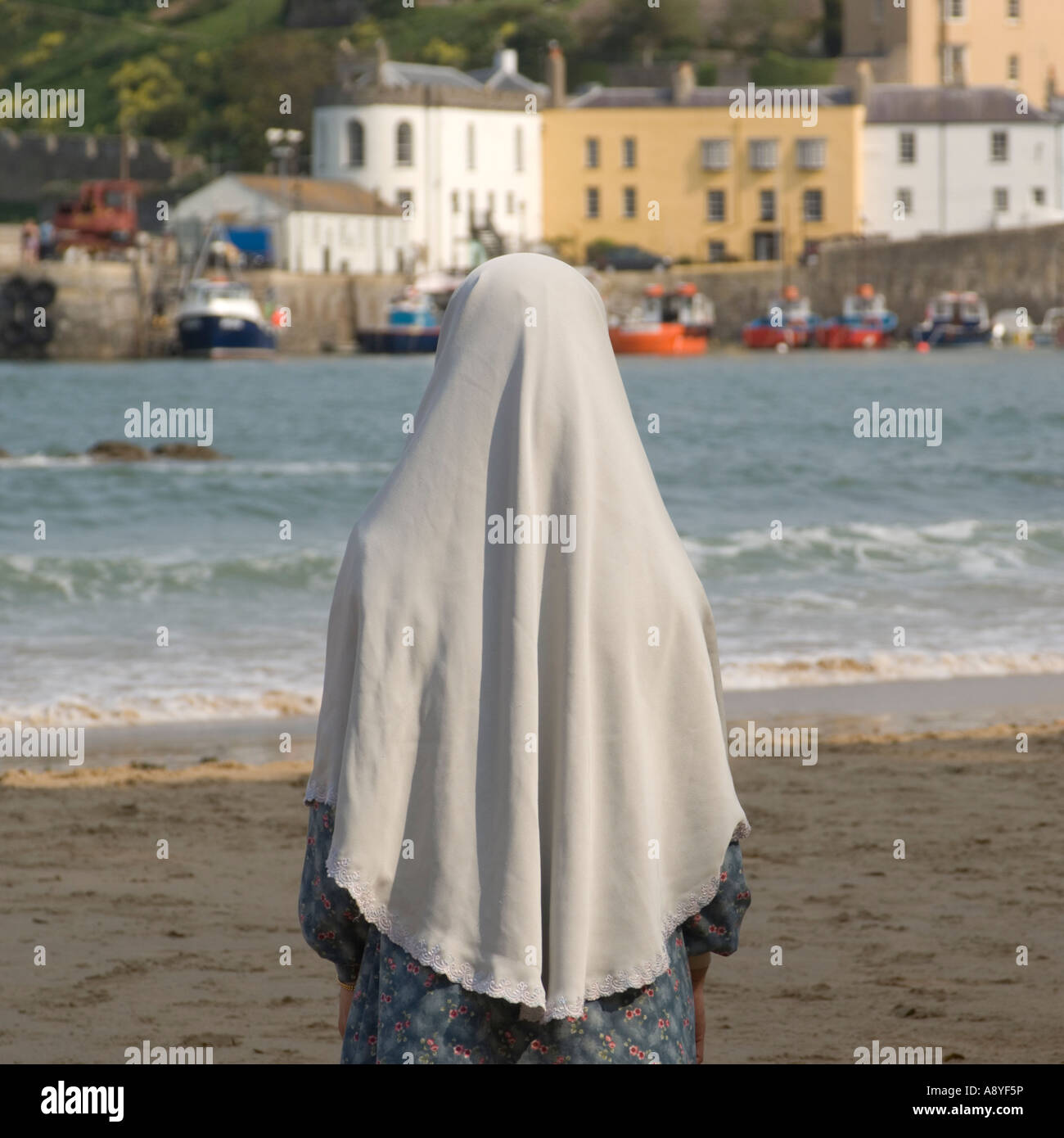 Rear view of a single moslem muslim woman standing on the beach tenby