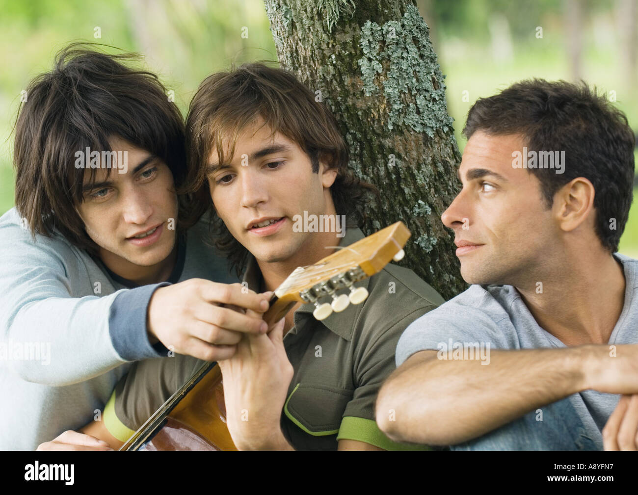 Young man showing friend hand position on guitar Stock Photo