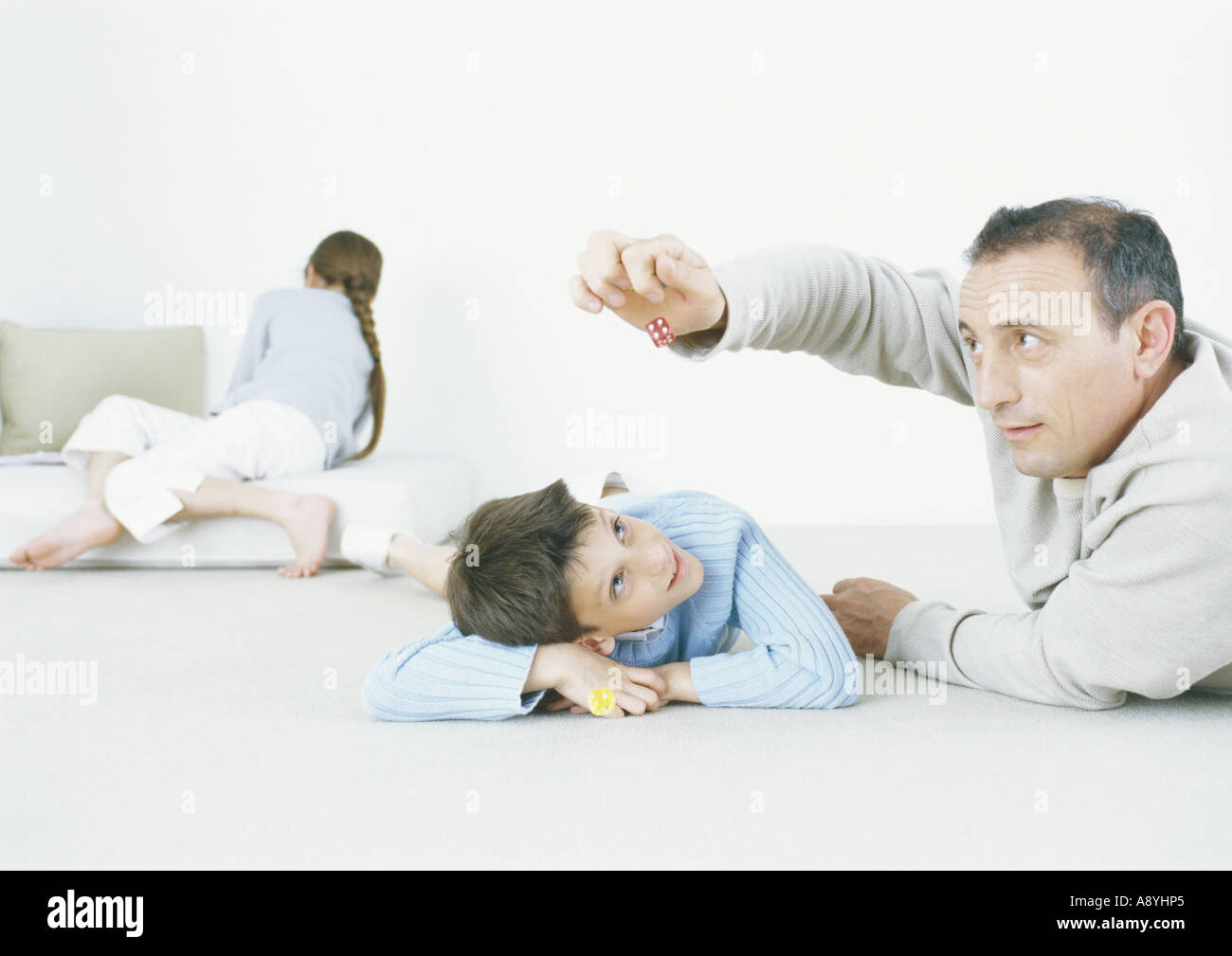 Man and son playing with dice on floor Stock Photo