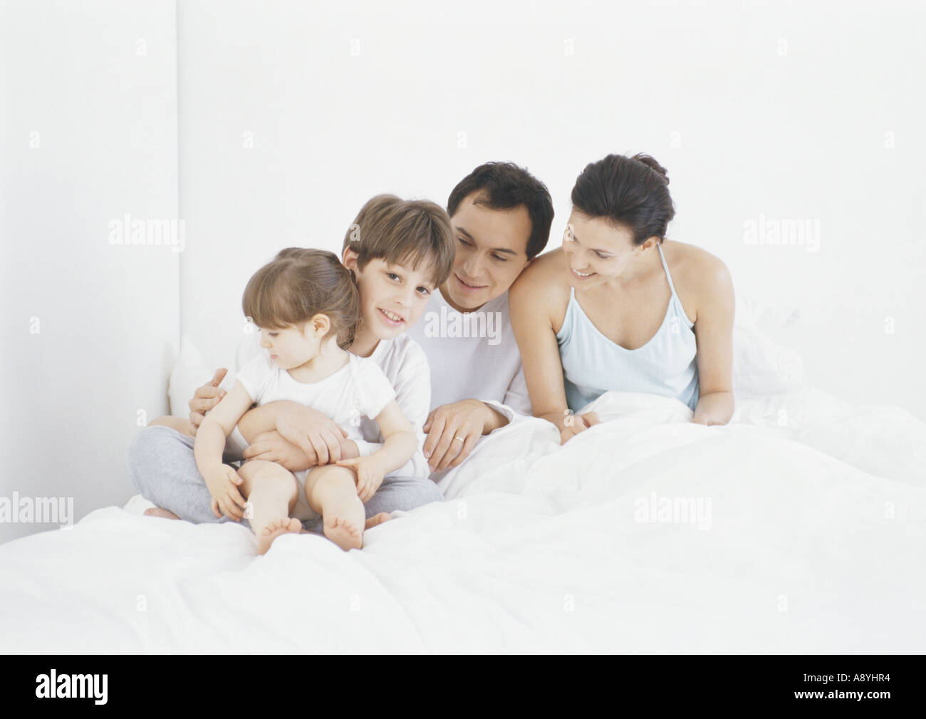 Family sitting in bed together Stock Photo