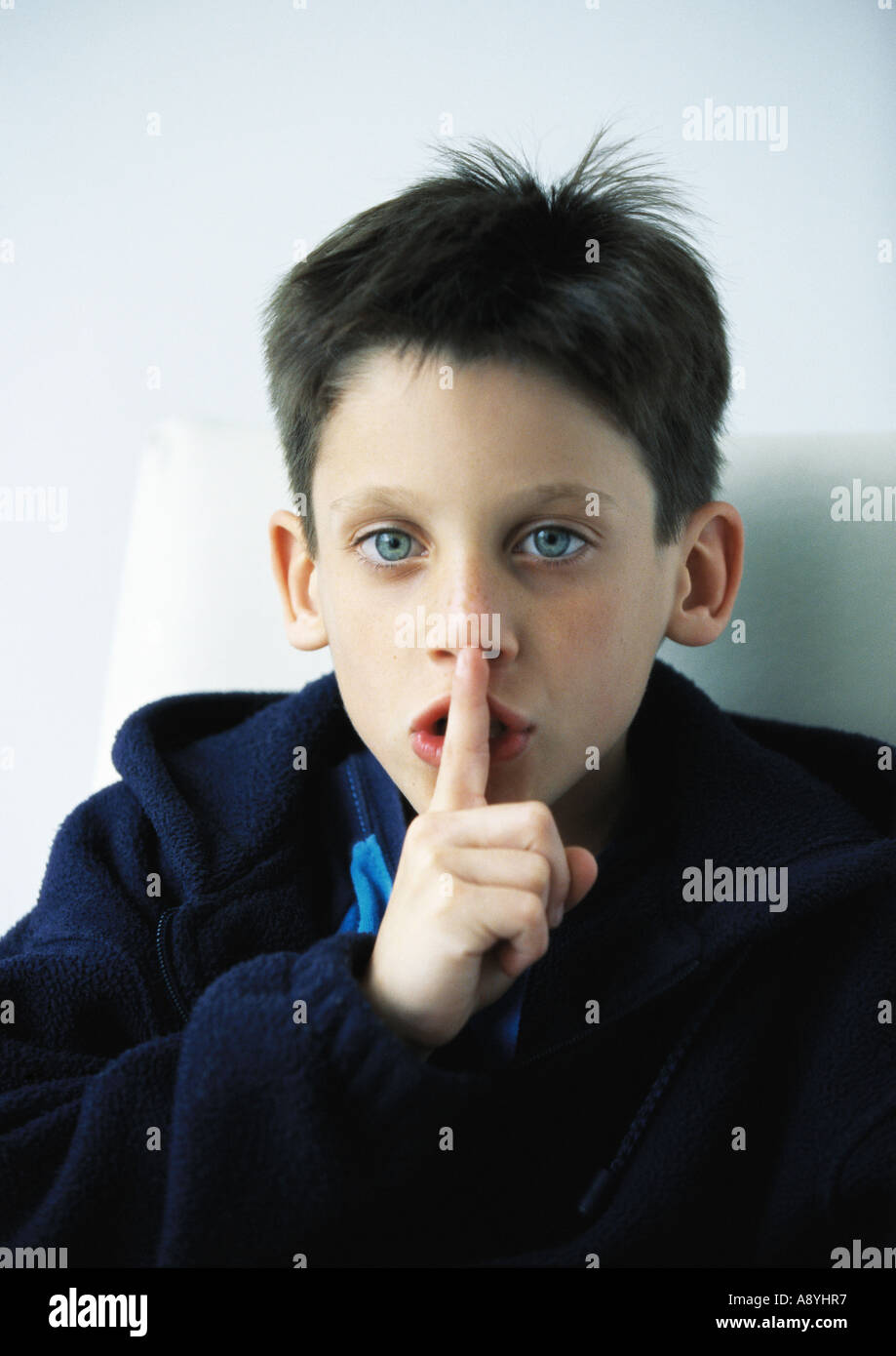 Boy with finger in front of lips Stock Photo