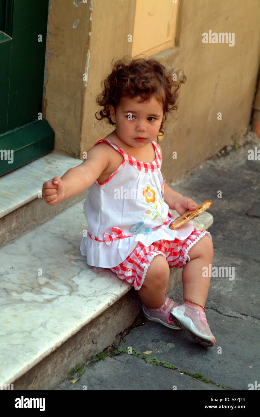Little Italian girl eating pizza sitting on step in a Pisa street Tuscany Italy EU Stock Photo