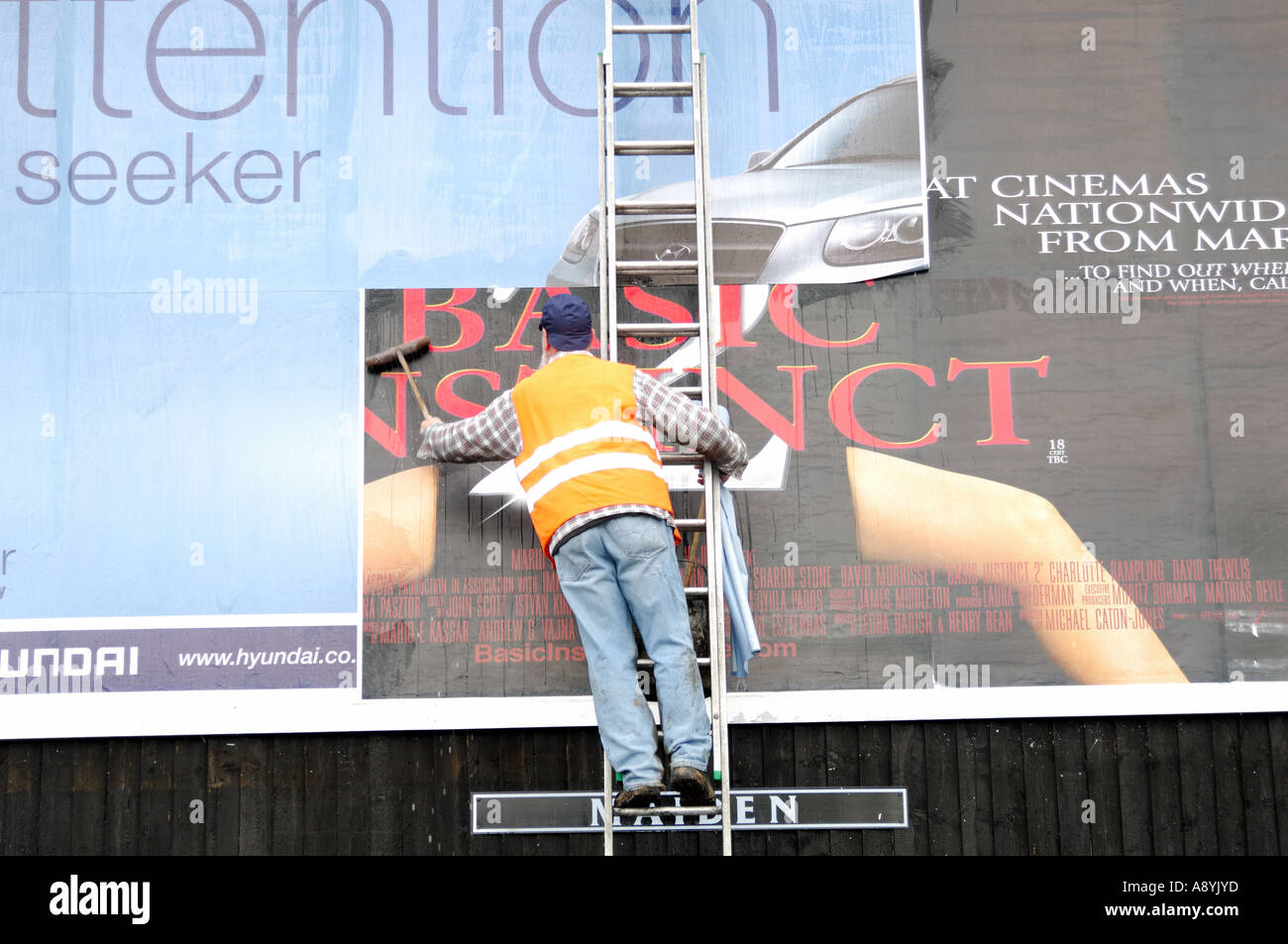 a male worker pastes a new advertisment to a billboard stock photo