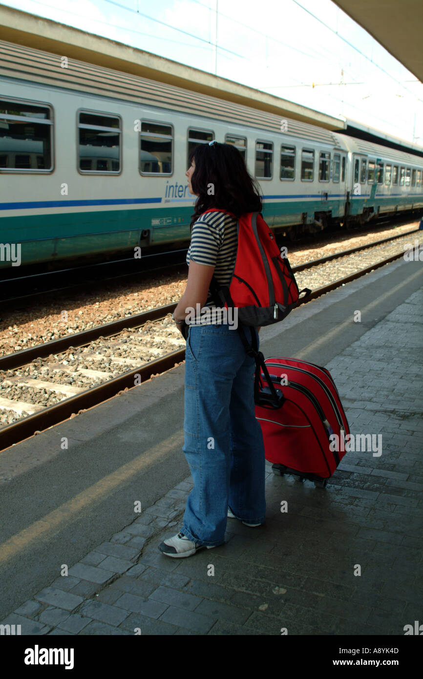 female passenger with red luggage waiting for train at Pisa central