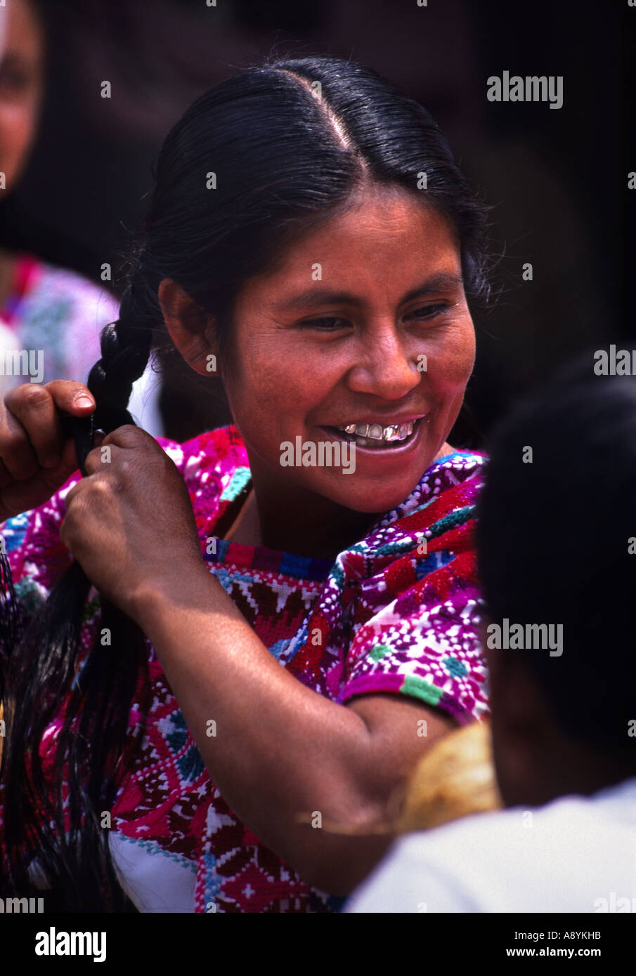 A ZINACANTAN MAYAN INDIAN GIRL PLAITING HER HAIR AT A MARKET IN SAN LORENZO ZINACANTAN CHIAPAS MEXICO Stock Photo
