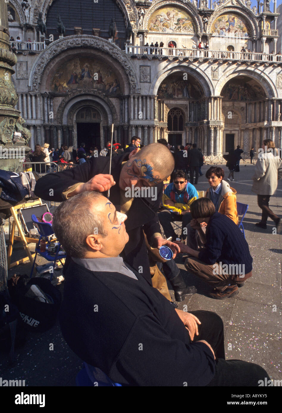 street artist painting the face of a tourist during the carnival in Piazza San Marco Venice Italy Stock Photo
