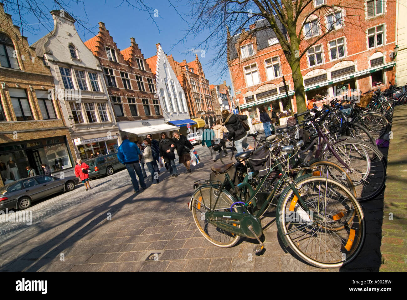 Horizontal wide angle of a typical streetscene in central Bruges, a row of parked bicycles on Steenstraat on a sunny day. Stock Photo