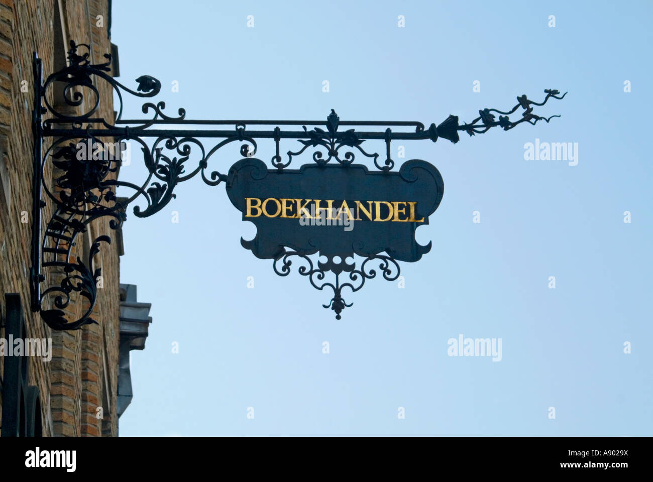 Horizontal close up of the detailed old fashioned wrought iron shop signs against a blue sky Stock Photo