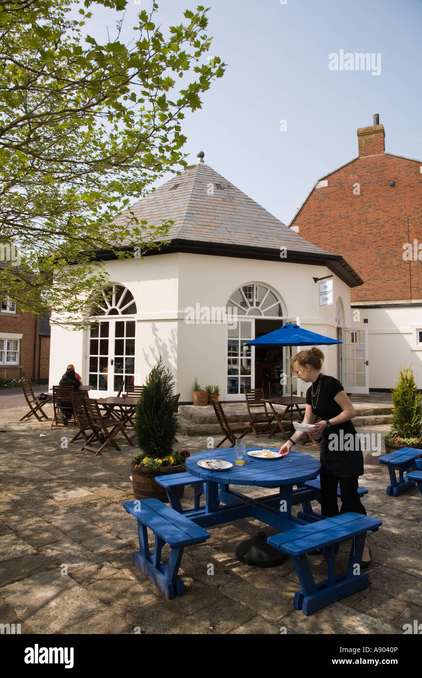 Waitress clears table at the Octagon cafe Poundbury Dorchester Dorset UK Stock Photo