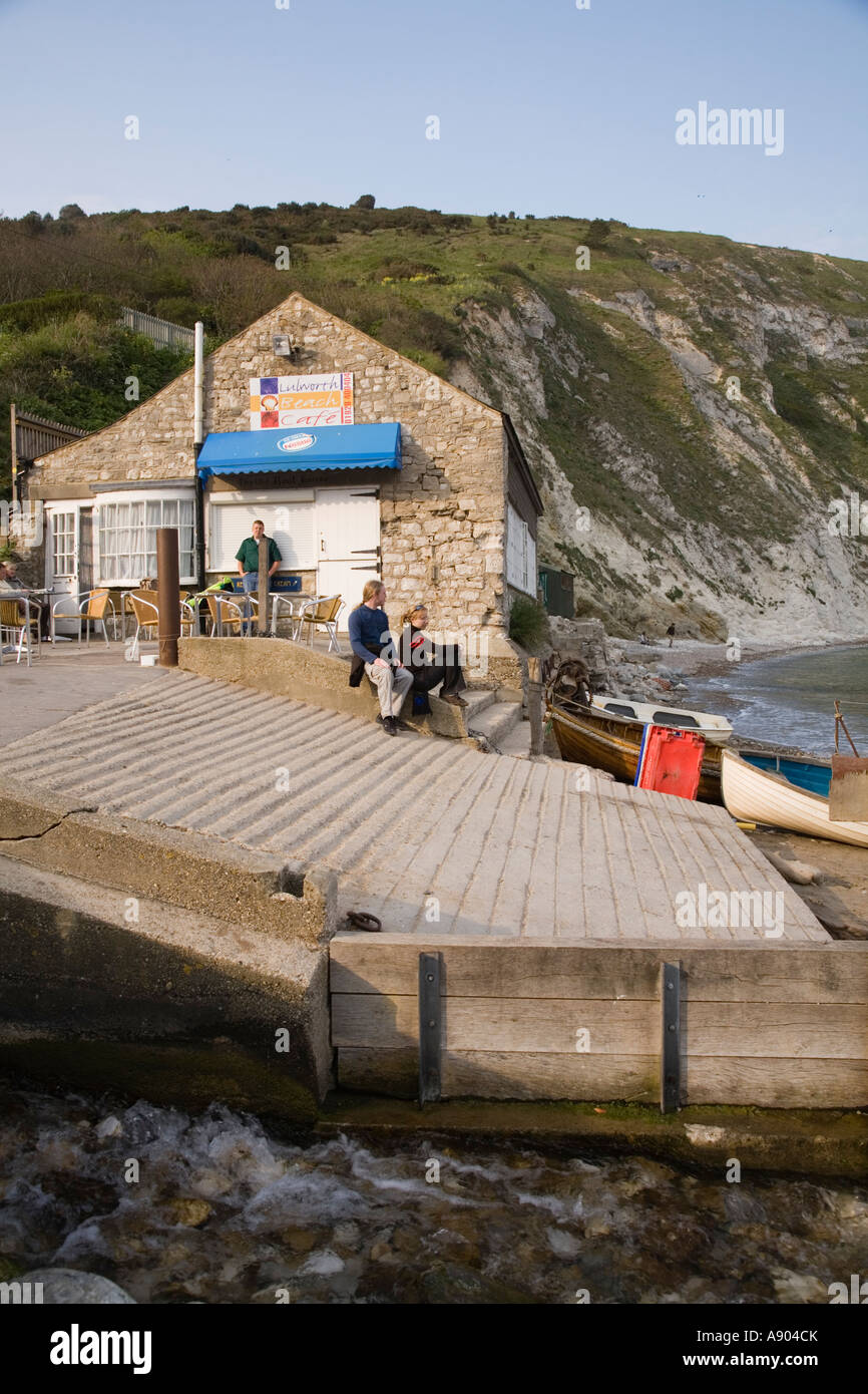 Slipway for boat launching and tourist couple outside Lulworth Cove beach cafe Dorset UK Stock Photo