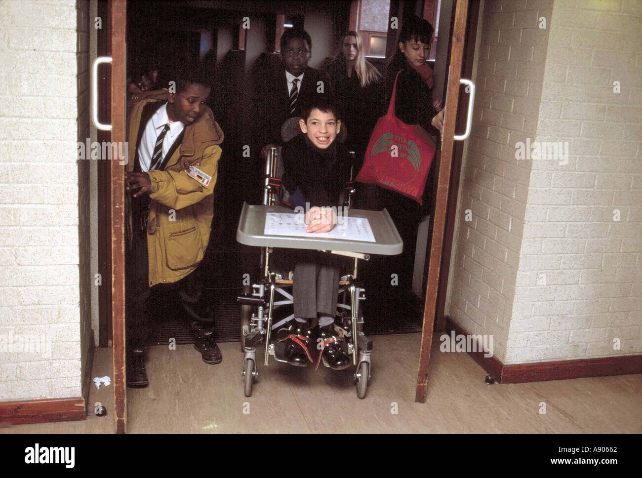 Disabled boy in motorized wheelchair leaving integrated classroom of secondary comprehensive school Stock Photo