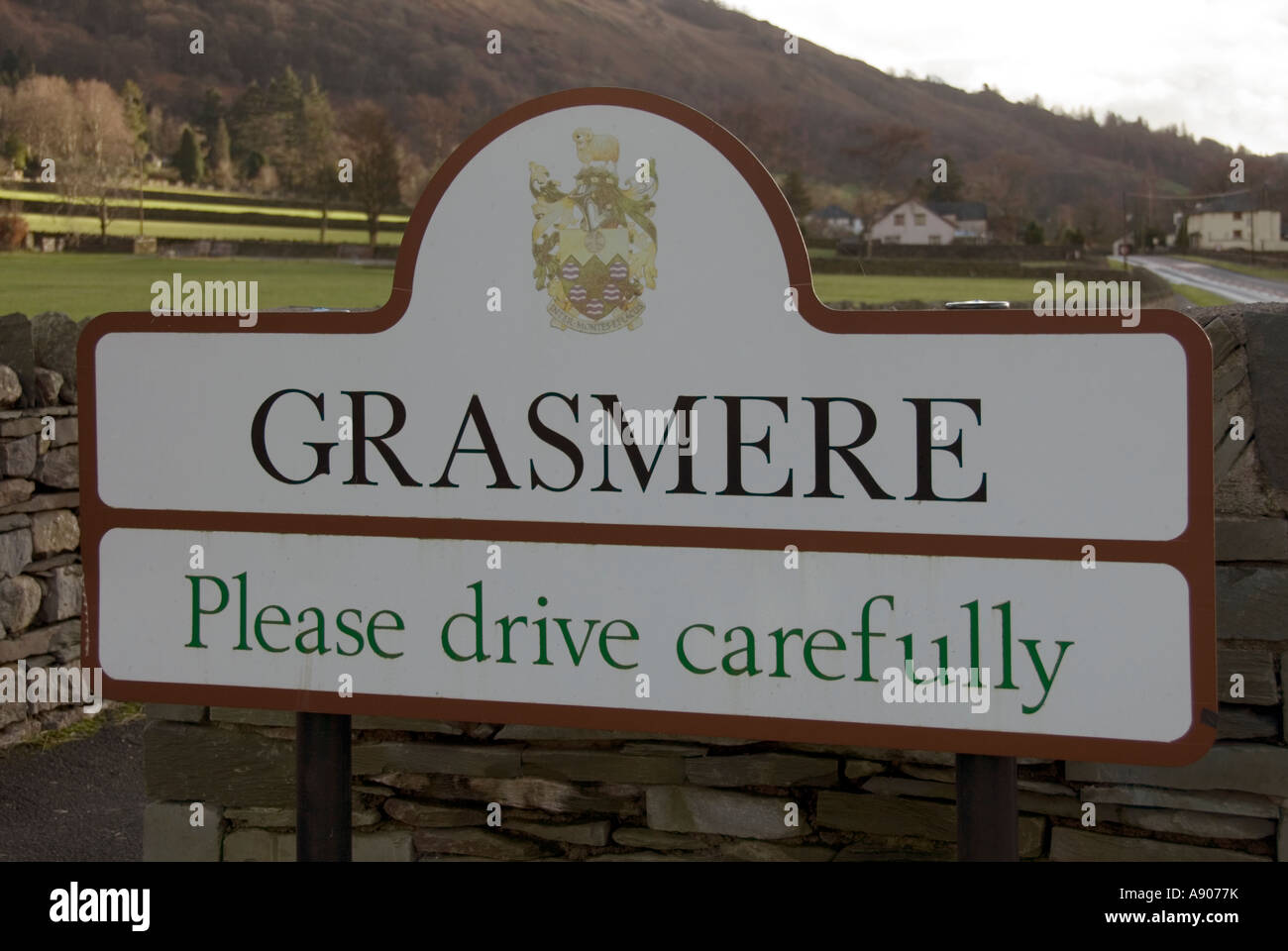 Grasmere Lake District national park village boundary sign & coat of arms  drive carefully slogan for motorists beside A591 road Cumbria England UK  Stock Photo - Alamy