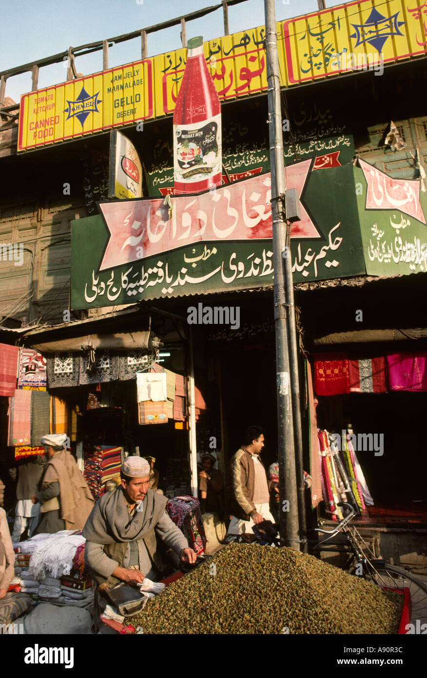 Pakistan NWFP Peshawar Qissa Khawani Bazaar raisin seller below Urdu Language hoardings Stock Photo