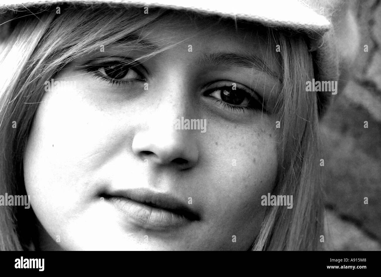 Close up horizontal portrait in black and white, of face of pretty young blonde haired girl wearing hat Stock Photo
