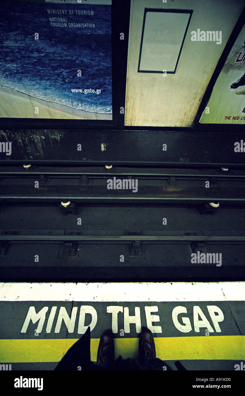 A persons feet by a Mind the Gap warning on a London underground station platform Britain UK Stock Photo