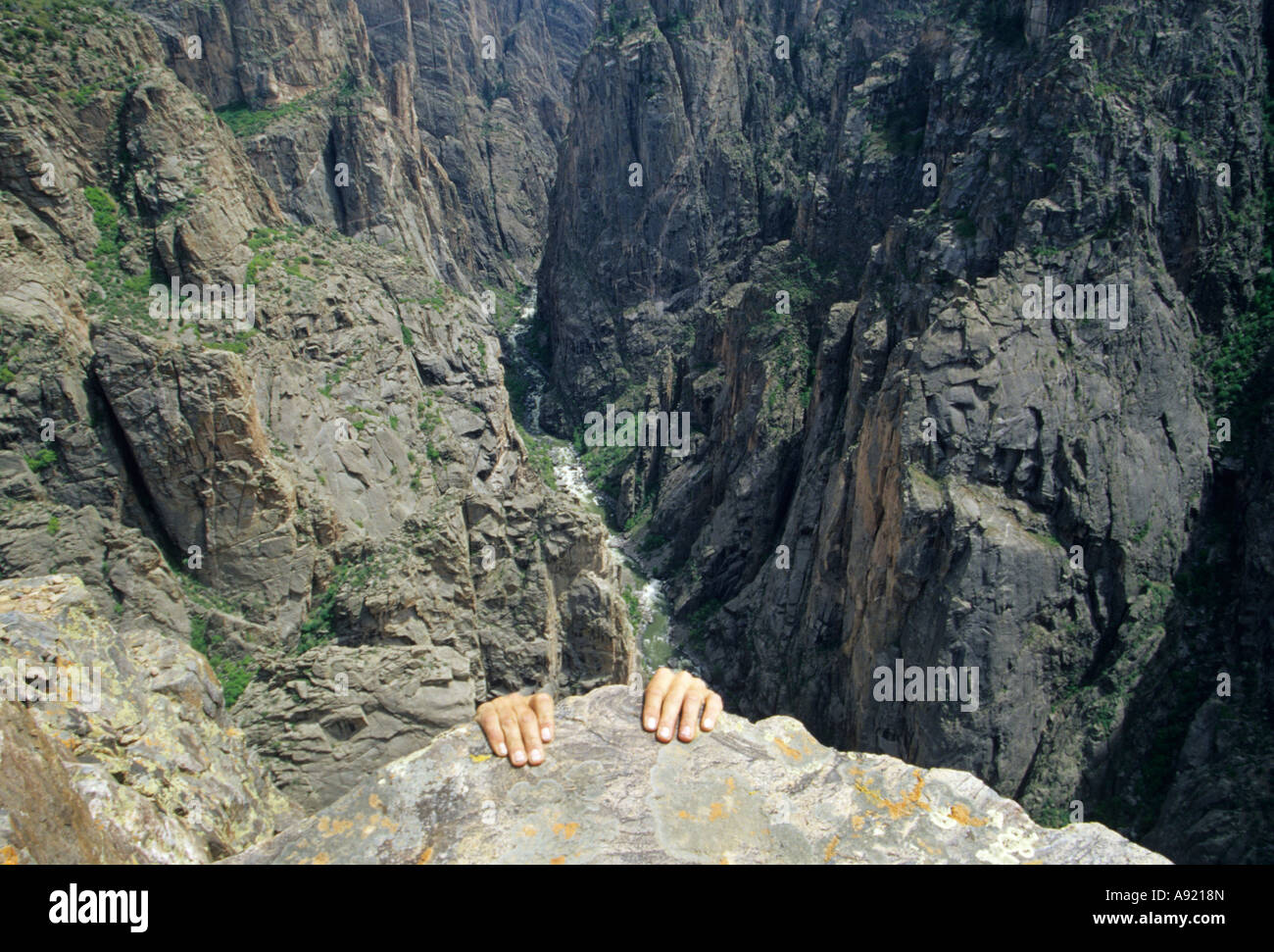 hands holding on the rock with the Black Canyon in the backround Black Canyon National Park Colorado Stock Photo