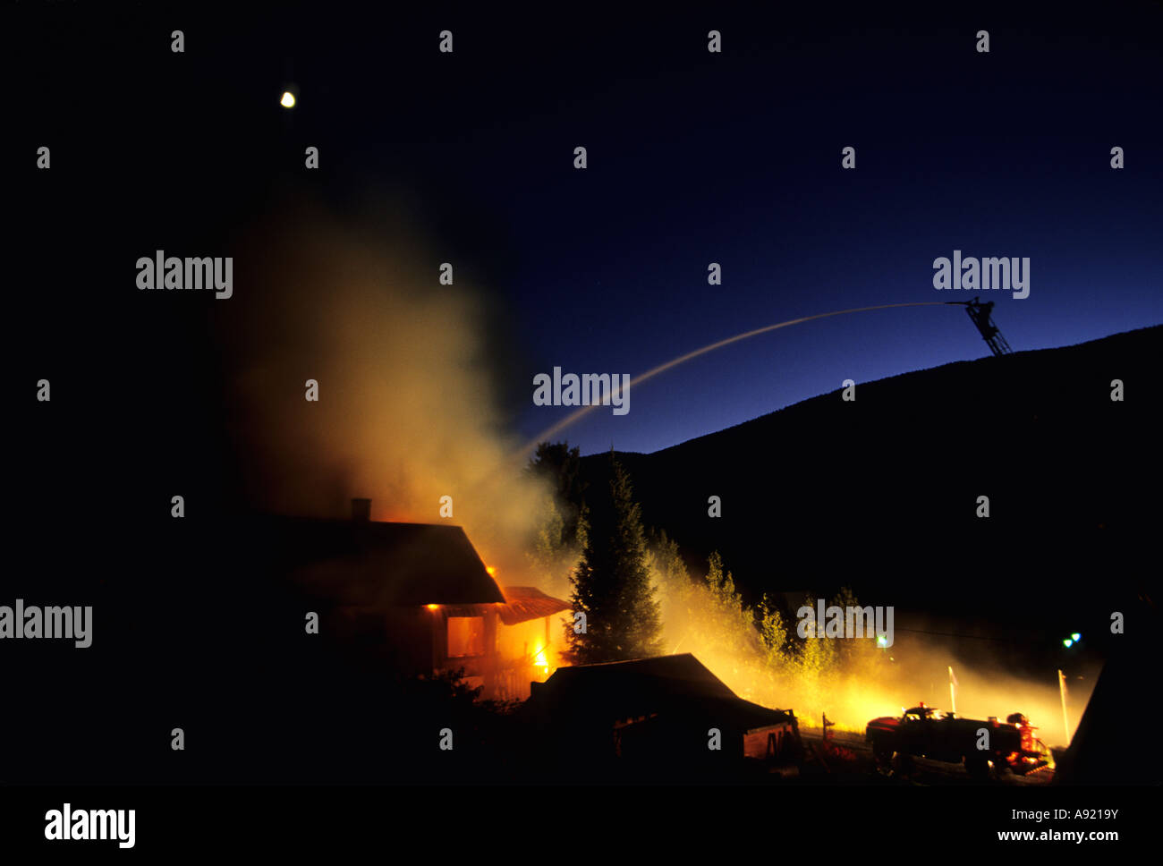 fireman on ladder hosing down burning house Rico Colorado Stock Photo