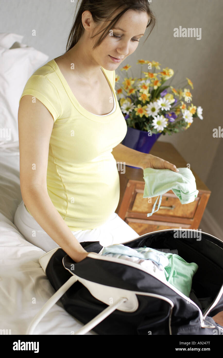 Pregnant woman putting clothes in bag Stock Photo