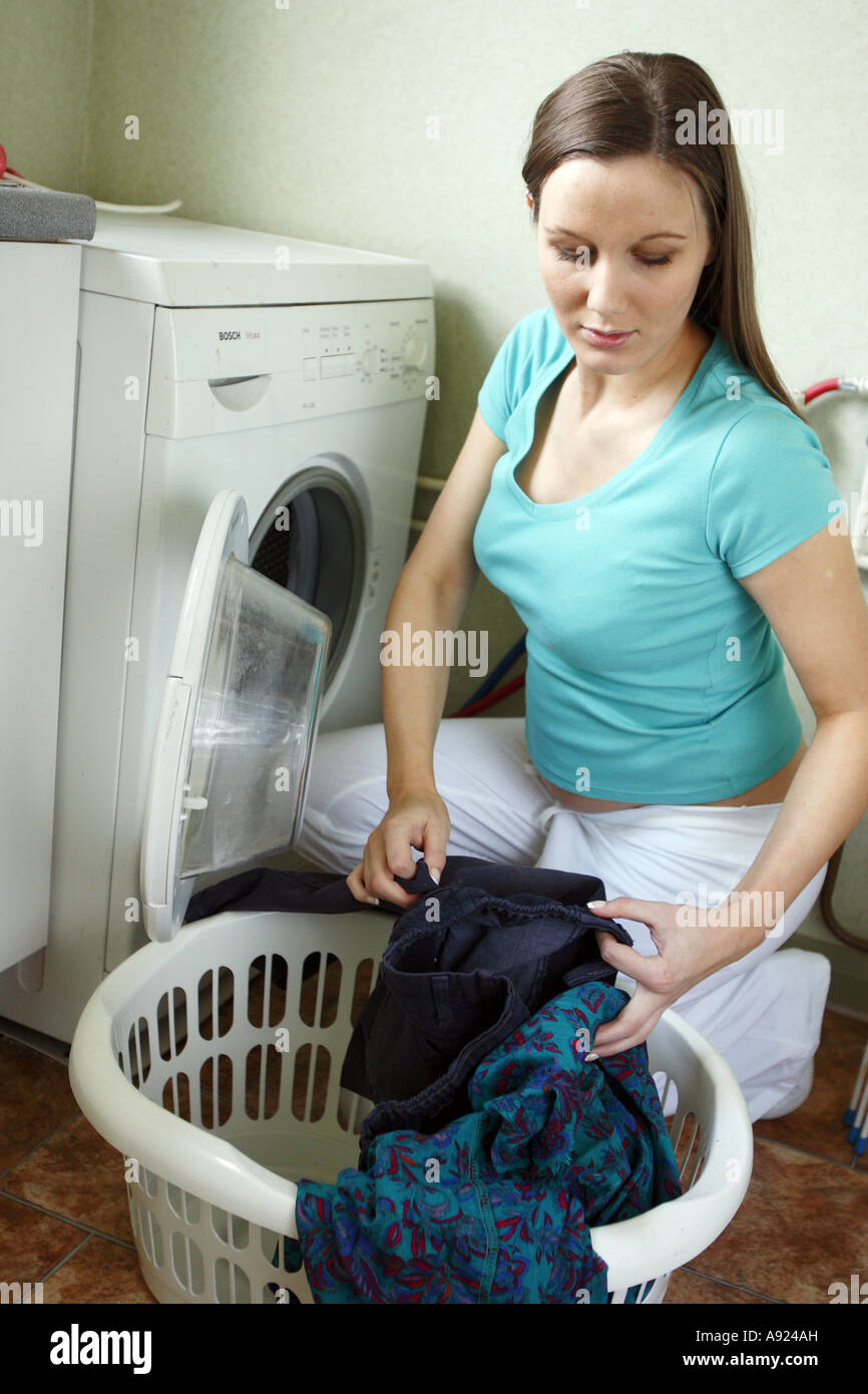 Pregnant woman taking clothes from washing machine Stock Photo Alamy
