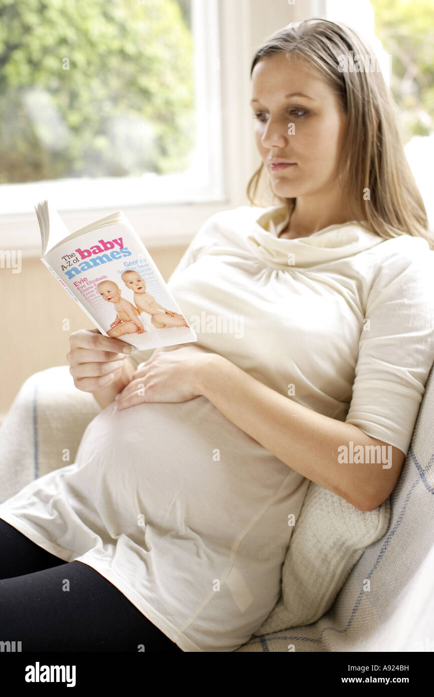 Pregnant woman reading book with baby names Stock Photo