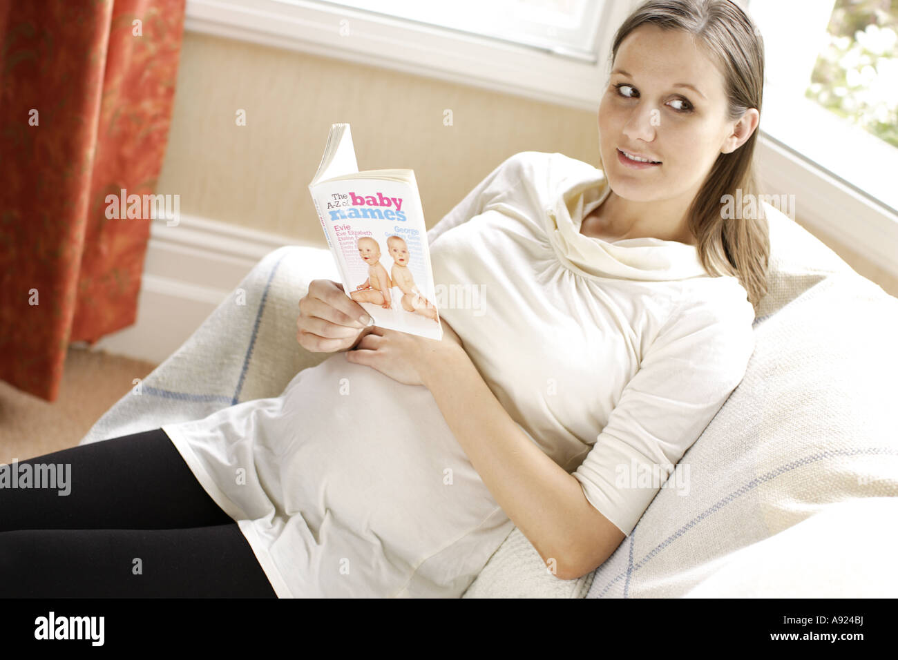 Pregnant woman reading book with baby names Stock Photo