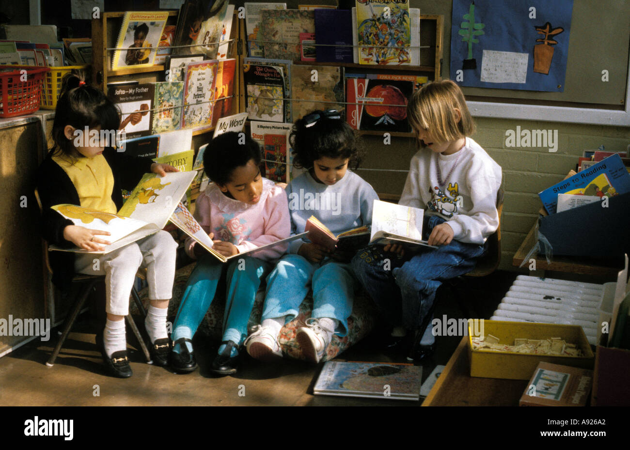 A group of children quietly reading in the book corner of the classroom Stock Photo