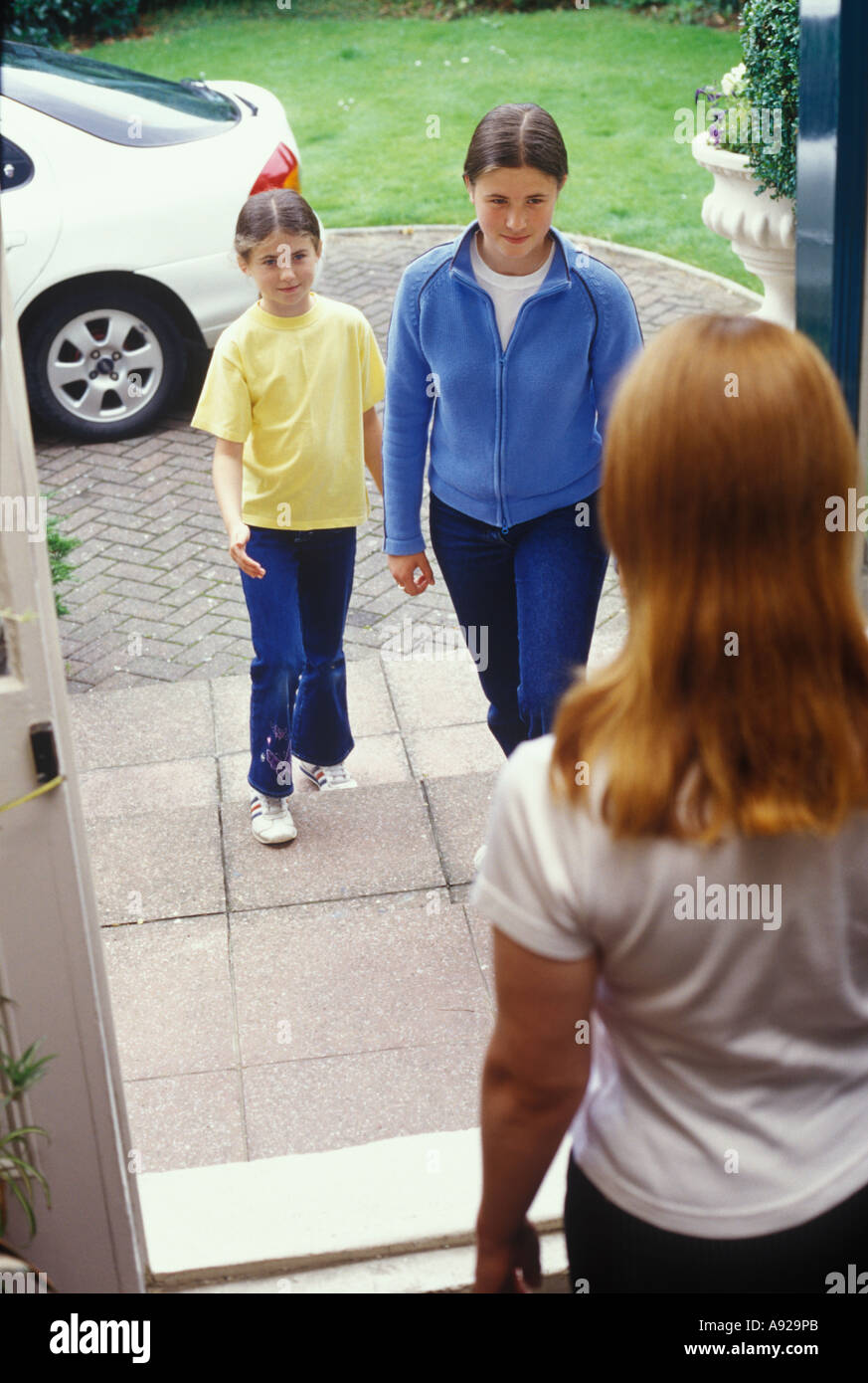 woman opening the door to two children Stock Photo