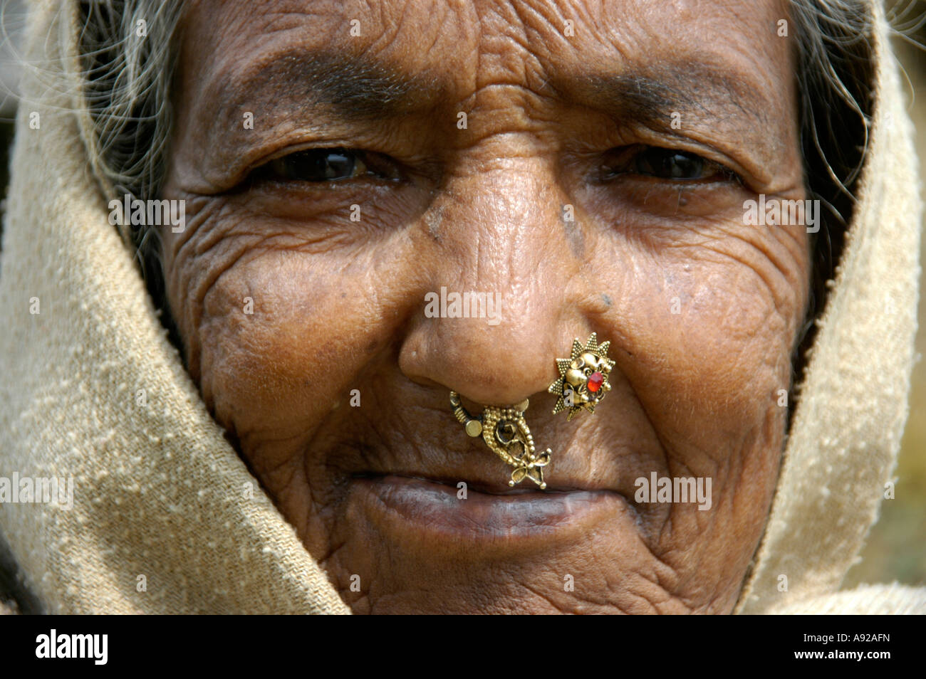 Portrait of an old lady with a pierced nose in the hood near Pokhara Nepal Stock Photo
