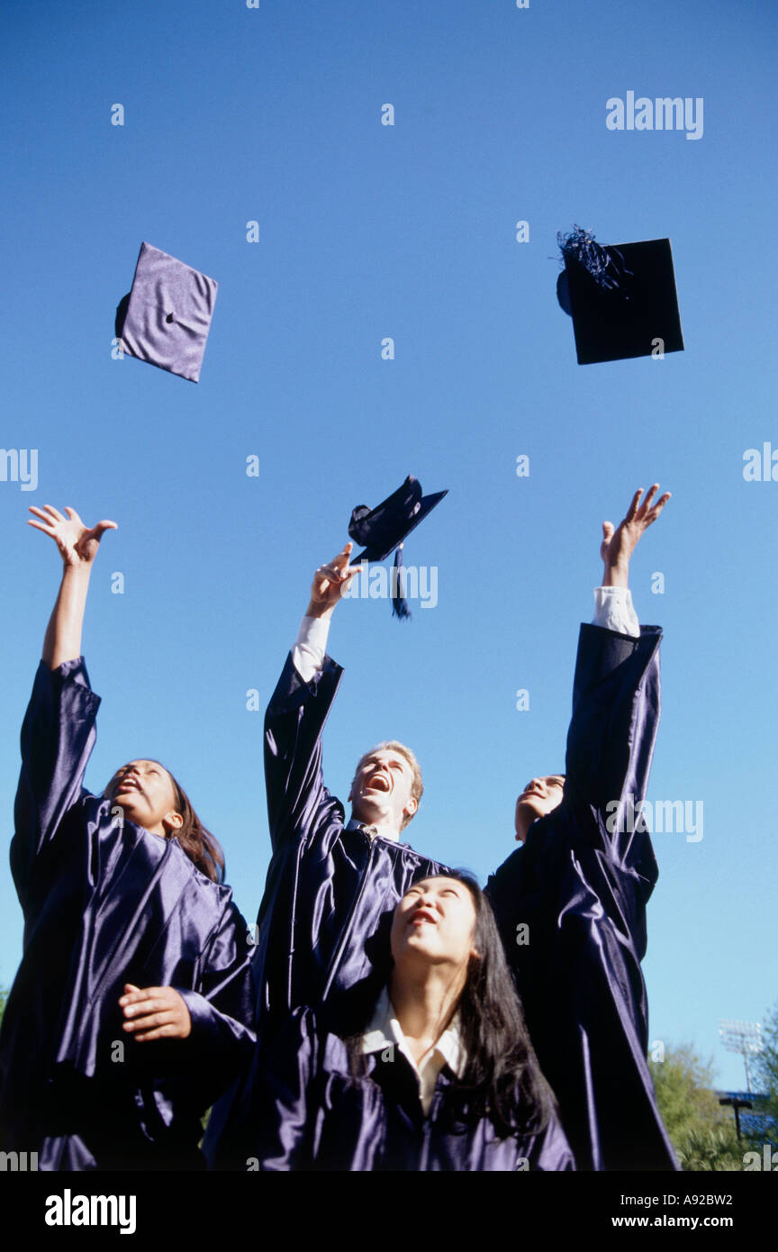 Low angle view of a group of young graduates throwing their graduation caps in the air Stock
