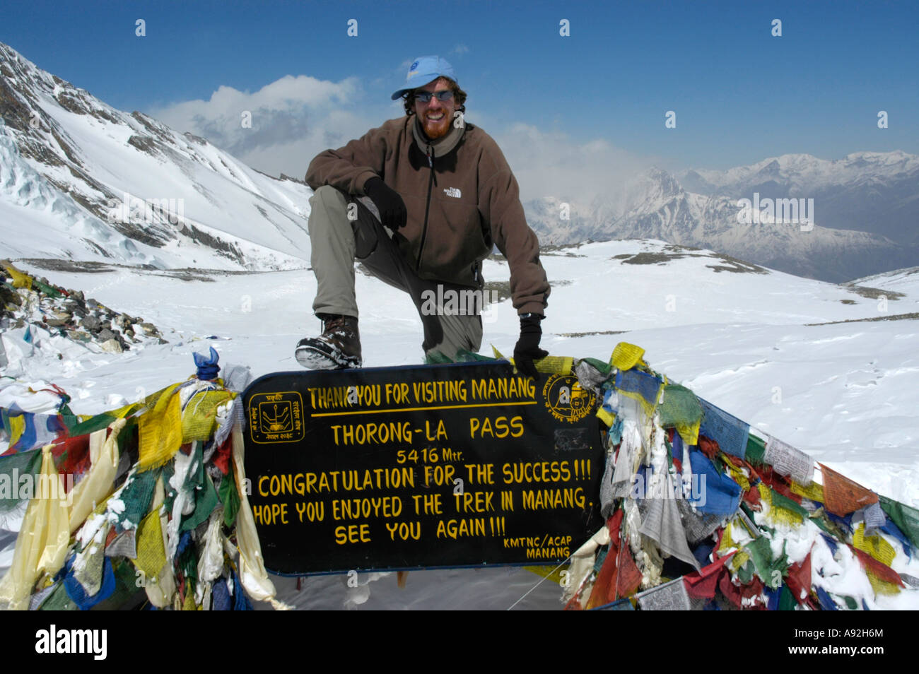 Successful mountaineer at the sign with prayer flags in the snow Thorung La Pass 5416 m Annapurna Region Nepal Stock Photo