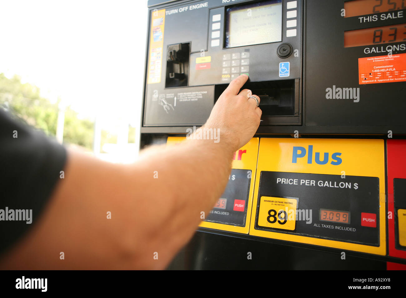 Man's hand pressing the keypad of a fuel pump at a gas station Stock