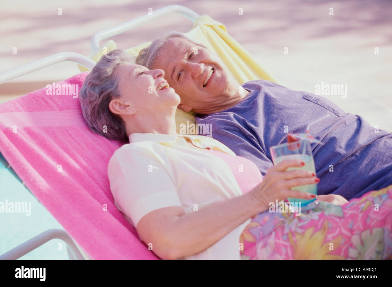 Senior couple resting on lounge chairs at the poolside Stock Photo - Alamy