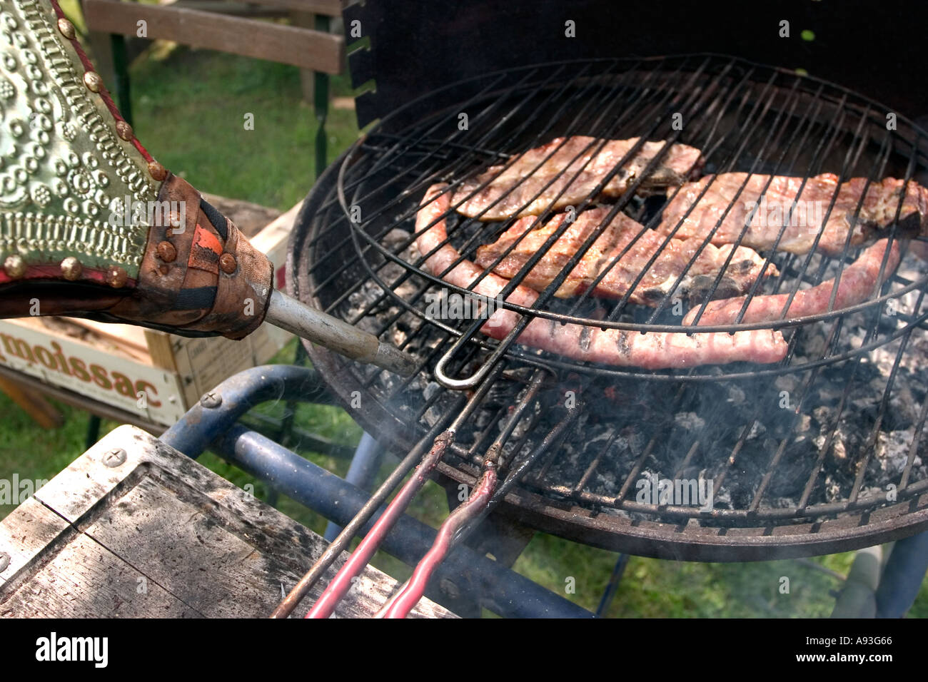 Grilled meat on barbecue grill with fourch and hand of man Stock Photo