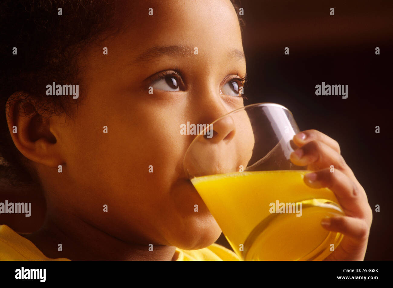 Infant four year old girl drinking a glass of orange juice in her home kitchen Stock Photo