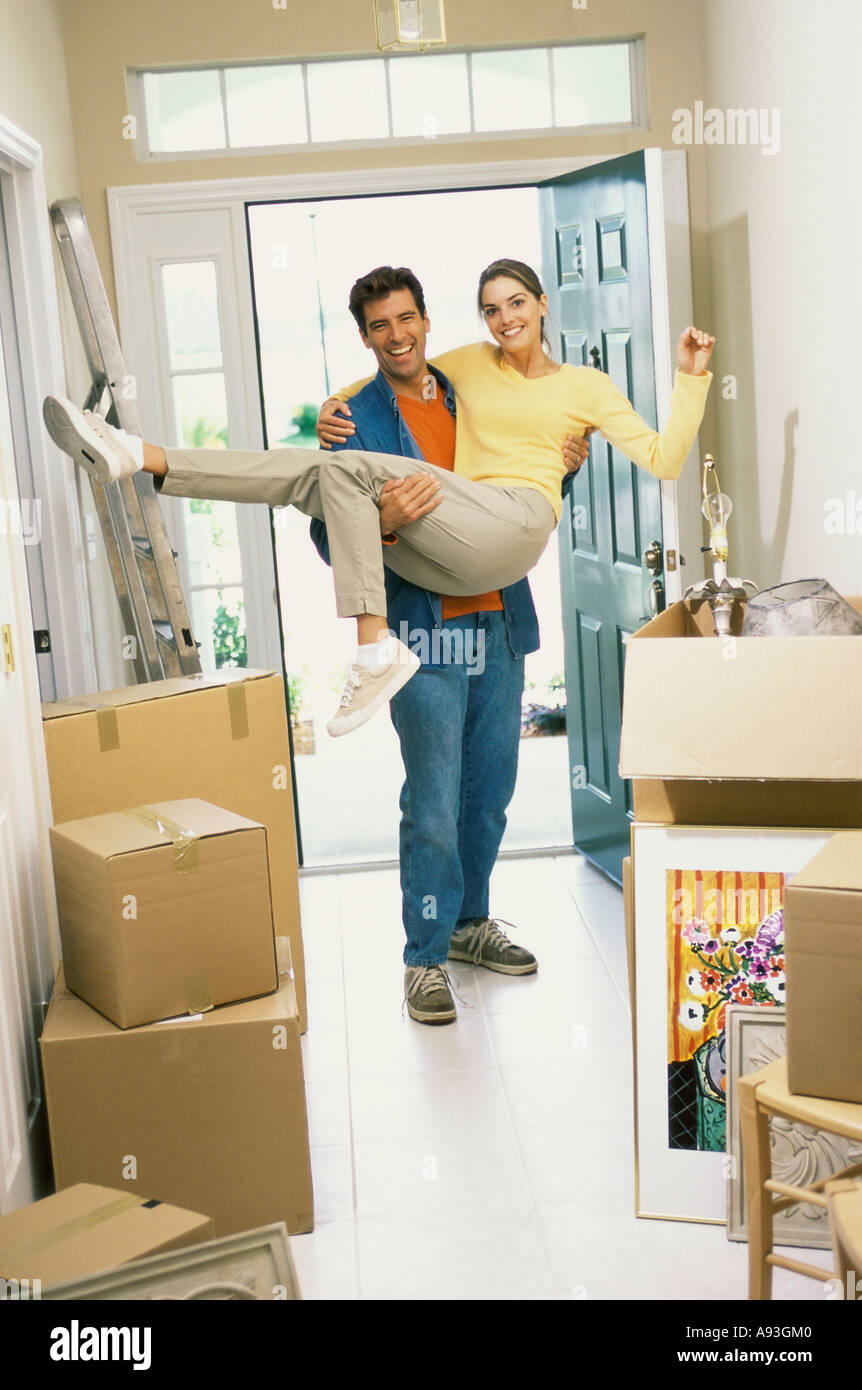 Young man carrying a young woman over the threshold of their new home